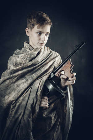 Tenn boy dressed in camouflage robe with a gun playing soldierの写真素材