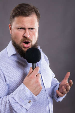 Bearded emotional singer with micriphone dressed in shirtの写真素材