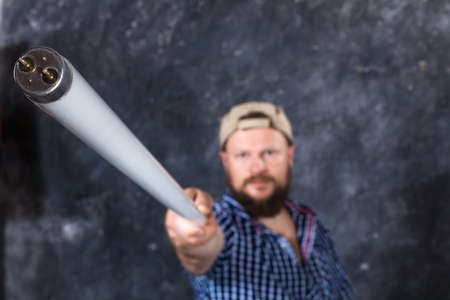 Solid bearded man at casual clothes with a fluorescent lamp looks like stickの写真素材