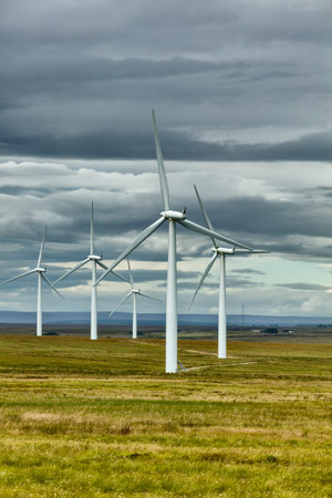 Landscape with wind turbines on cloudy sky background.