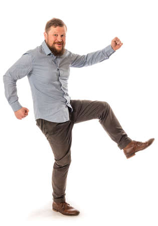 Joyful bearded man in shirt stepping studio portrait on white background.の写真素材