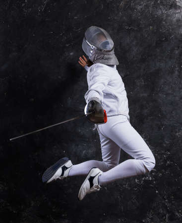 Teenage girl fencer dressed in uniform with epee and helmetの写真素材