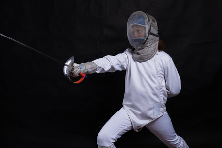 Teenage girl fencer dressed in uniform with epee and helmet