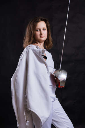Teenage girl fencer dressed in uniform with epee and helmetの写真素材