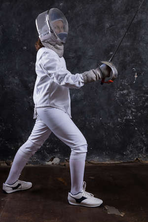 Teenage girl fencer dressed in uniform with epee and helmetの写真素材