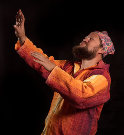 Joyful bearded man in bright orange shirt dancing