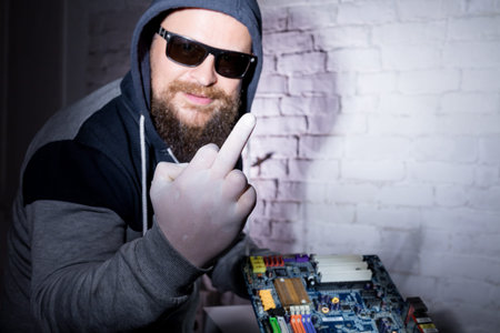 Bearded hacker in sunglasses and hoodie cracking the hardware