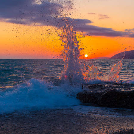 Beautiful shoreline scene with waves at sunset beamsの写真素材
