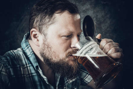 Matured smiling bearded man in shirt with beer mugの写真素材