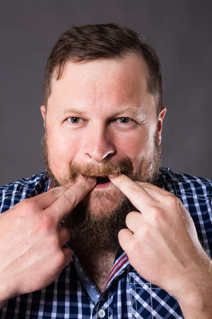 Joyful bearded man in shirt whistling studio portraitの写真素材