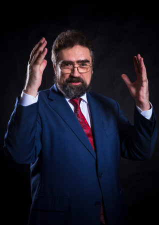 Mature businessman dressed in blue suit with red tie studio portrait.