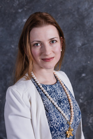 Cheerful middle aged woman in blue dress and white jacket