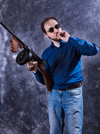 Mature man in sunglasses with tommy gun