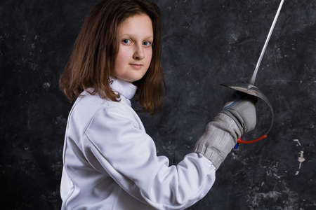 Teenage girl fencer dressed in uniform with epee and helmetの写真素材