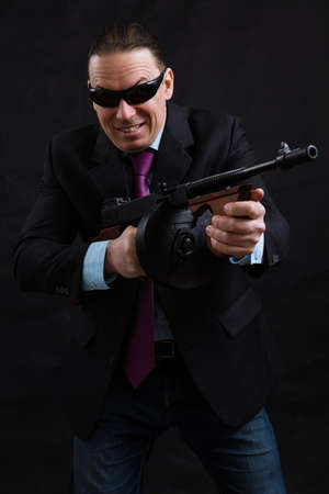 Mature gangster in sunglasses dressed in suit with tommy gunの写真素材