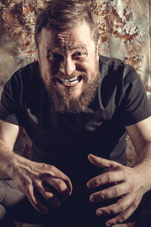 Mature bearded man in black t-shirt emotional studio portrait.の写真素材