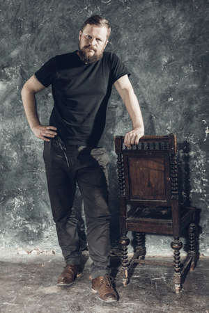 Mature bearded man dressed in t-shirt sitting on chairの写真素材