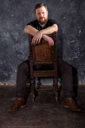 Mature bearded man dressed in t-shirt sitting on chairの写真素材