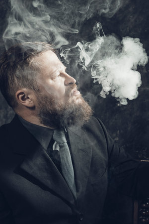 Solid confident bearded man in suit smoking