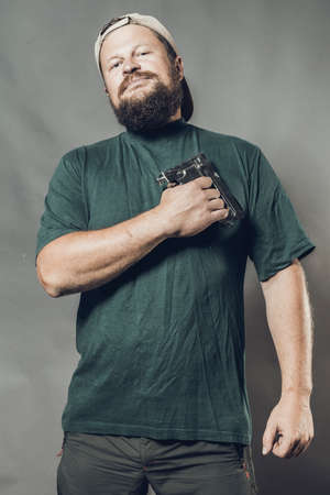 Joyful bearded craftsman in green t-shirt having fun with staple gunの写真素材