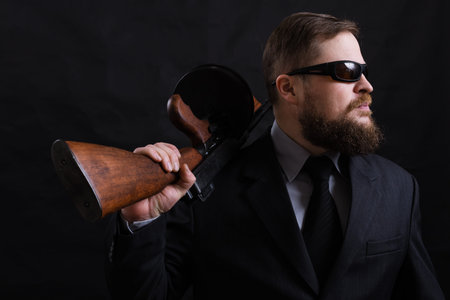 Mature bearded man in sunglasses dressed in suit with tommy gunの写真素材