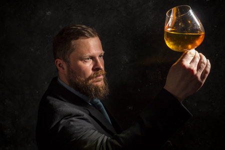 Solid confident bearded man in suit with glass of whisky