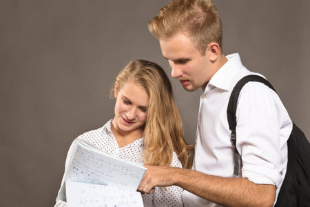 Two students young man and woman watching papers