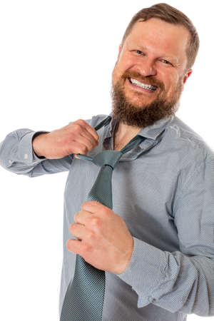 Cheerful bearded man dressed in shirt rips off his tieの写真素材