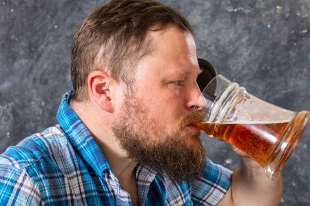 Matured smiling bearded man in shirt with beer mugの写真素材