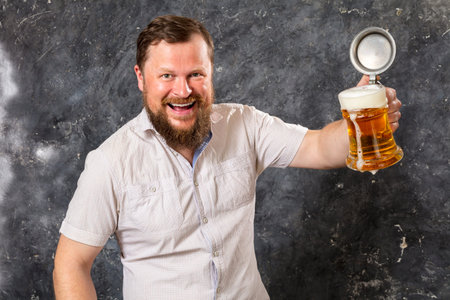 Matured smiling bearded man in shirt with beer mugの写真素材