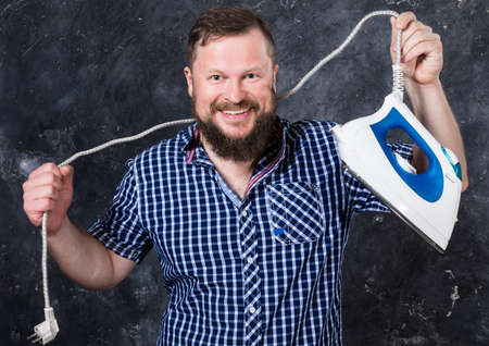 Solid bearded man at casual clothes having fun with ironの写真素材