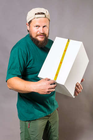 Joyful bearded craftsman in green t-shirt with tape measureの写真素材