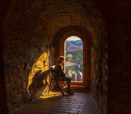 Boy looking at old stone window view on old town of Vilnius.の写真素材