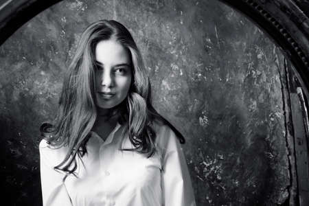 Beautiful young woman looking on her reflection at the mirrorの写真素材