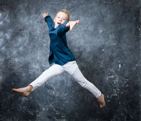 Young dancer dressed in white jeans and blue shirt doing figures studio portraitの写真素材