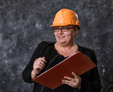 Middle-aged woman construction superintendent in helmet studio portrait.