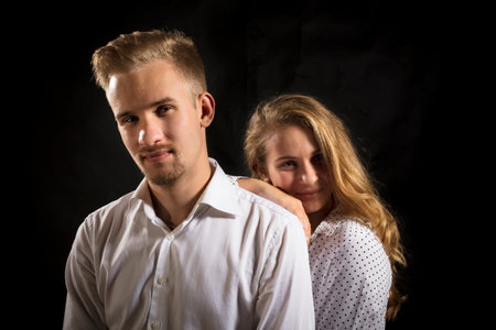Young beautiful couple studio portrait on black background.の写真素材