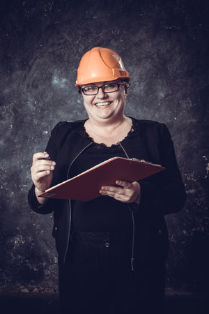 Middle-aged woman construction superintendent in helmet studio portrait.の写真素材