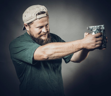 Joyful bearded craftsman in green t-shirt having fun with staple gunの写真素材