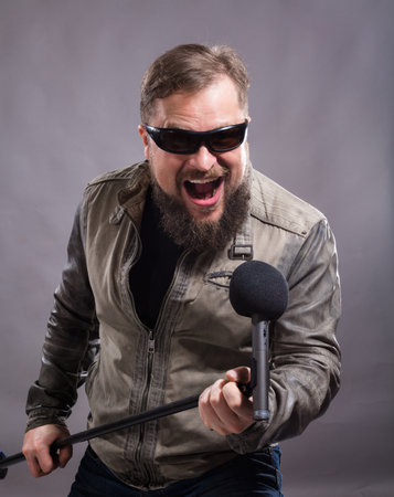 Bearded emotional rock singer with microphone studio portrait.の写真素材
