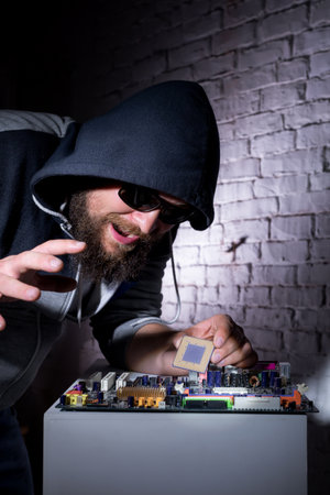 Bearded hacker in sunglasses and hoodie cracking the hardwareの写真素材
