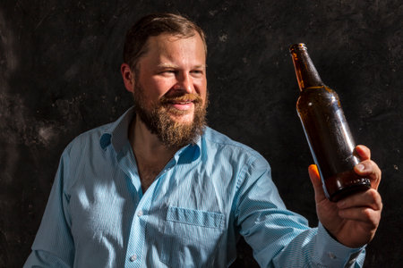 Solid bearded smiling man in shirt with bottle of beerの写真素材