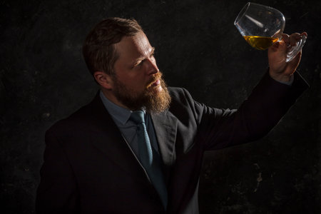 Solid confident bearded man in suit with glass of whiskyの写真素材