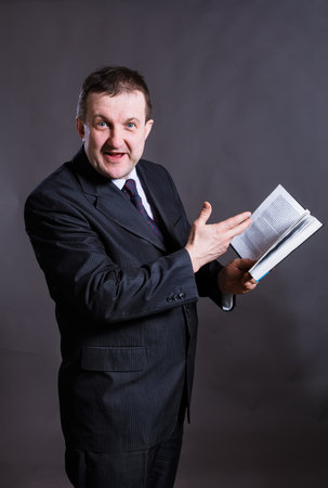 Middle aged solid tutor with book studio portrait.の写真素材