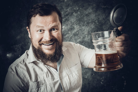 Matured smiling bearded man in shirt with beer mugの写真素材