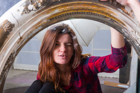Young longhaired beautiful woman sitting in front of the vintage mirrorの写真素材