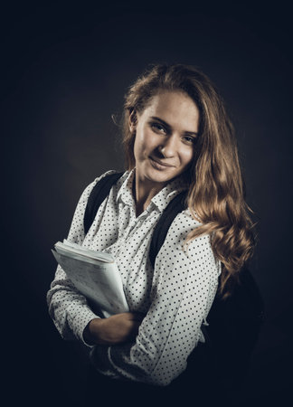 Young beautiful longhaired student girl with papers looks happyの写真素材