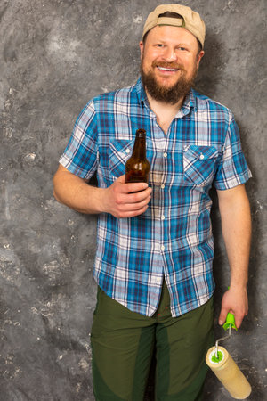 Joyful bearded foreman has a break with bottle of beerの写真素材