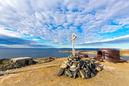 Military bunker of ww2 on Barents sea shoreline and christian crossの写真素材