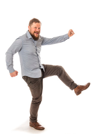 Joyful bearded man in shirt stepping studio portrait on white background.の写真素材